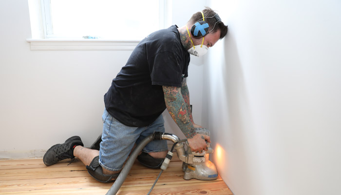 An Artisan Wood Floors team member sanding on-site using a dustless sanding system